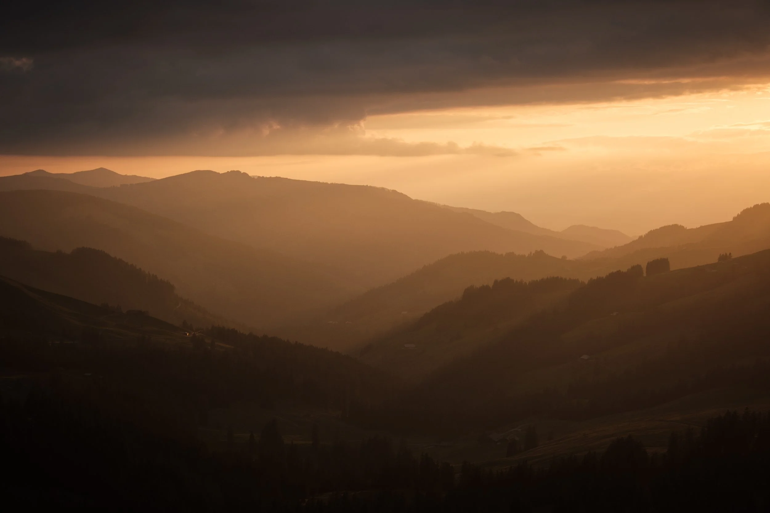 Berglandschaft bei Sonnenuntergang mit dunklen Wolken am Himmel